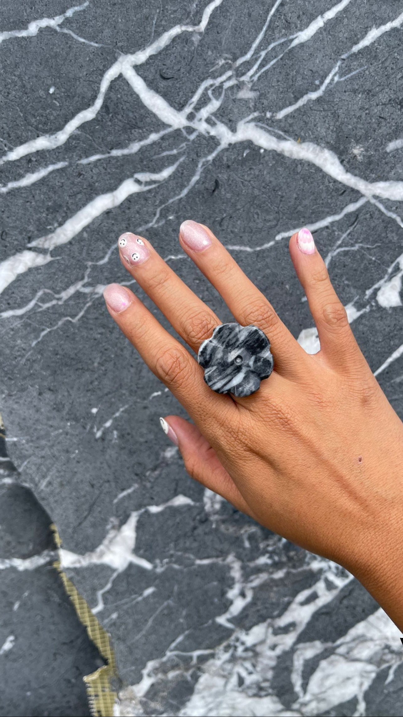 Foto Principal Piezas Personalizadas Mano con Anillo de Mármol Negro en Fondo de Mármol Negro